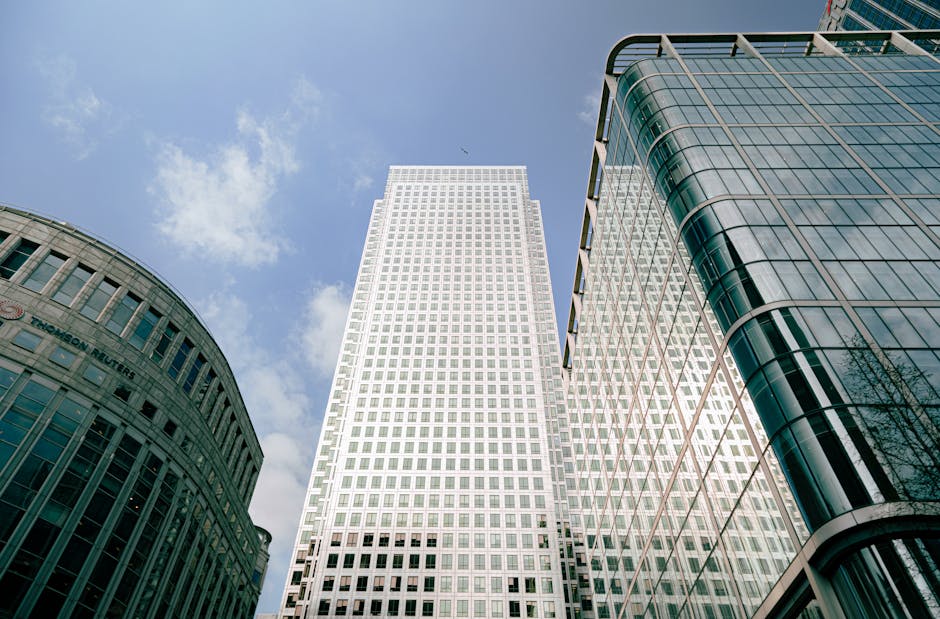 A cityscape scene featuring ongoing home relocation activities in Canary Wharf with a focus on furniture transport and packing preparations for a move. In the foreground, a circular water fountain wit